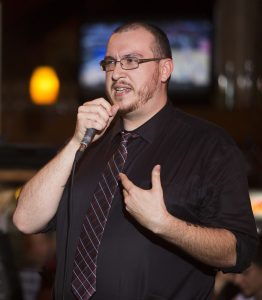 Man holding a microphone, telling a personal story.