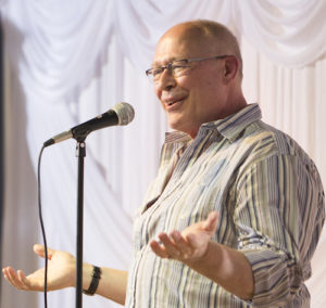Peter, wearing a striped shirt with the sleeves pushed up, gestures with both hands as he tells.