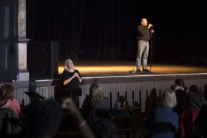 Dan Lococo on stage at The New Year Spectacular and an ASL interpreter in the same frame