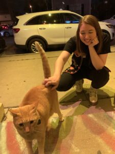 Lauren Instenes smiling and petting an orange, short haired cat