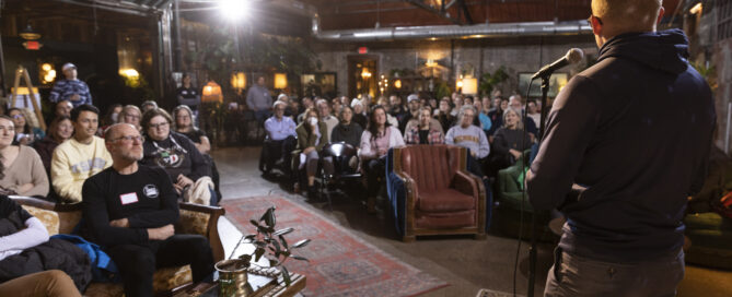 Audience looks ahead. Camera captures the back of storyteller