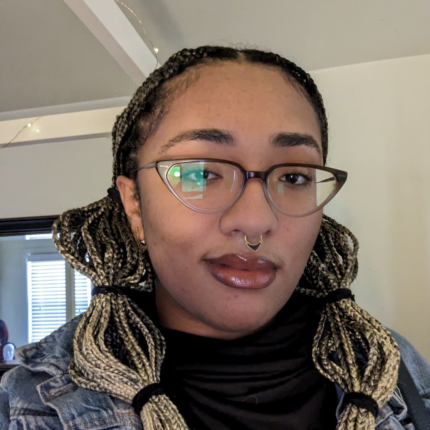 A Black non-binary person with braids and glasses.