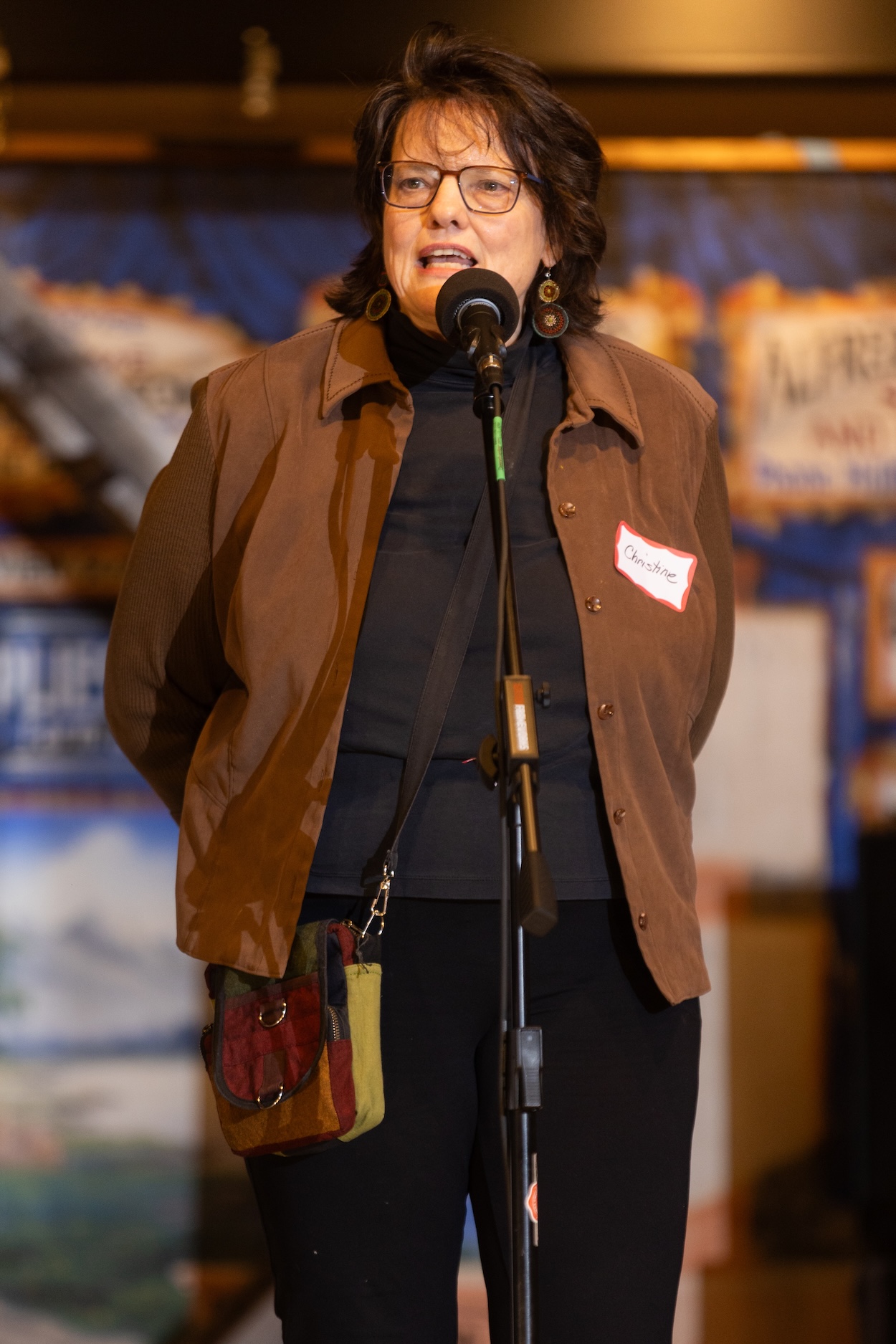 Person standing on a stage, speaking into a microphone.