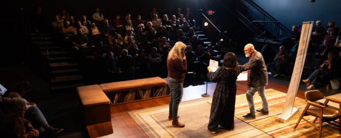 Three Ex Fabula volunteers on the Next Act Theater stage, preparing to announce the next storyteller to the audience