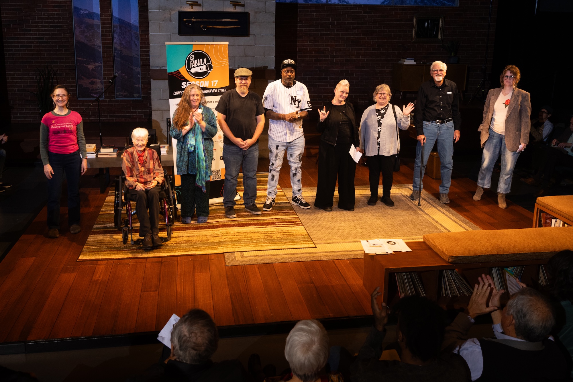 Nine storytellers standing in a row on the Next Act Theatre stage at the conclusion of a StorySlam
